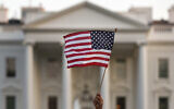 In this Sept. 5, 2017, file photo, a flag is waved outside the White House, in Washington. The Trump administration is extending a ban on green cards issued outside the United States until the end of 202 and adding many temporary work visas to the freeze, including those used heavily by technology companies and multinational corporations. (AP Photo/Carolyn Kaster, File)