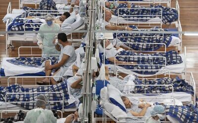 COVID-19 patients lie on beds in a field hospital built inside a gym in Santo Andre, on the outskirts of Sao Paulo, Brazil, June 9, 2020. (AP Photo/Andre Penner, File)