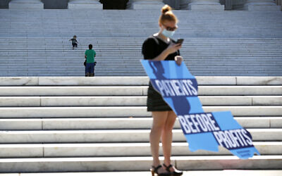 A child runs down the steps of the Supreme Court on Capitol Hill in Washington, June 29, 2020, as an anti-abortion protester holds a sign after the court struck down a Louisiana law regulating abortion clinics (AP Photo/ Patrick Semansky)