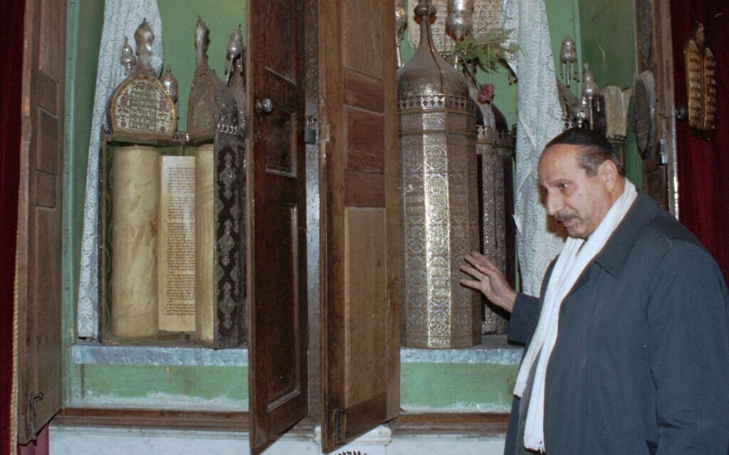 FILE - This Friday, January 21, 2000, file photo, Youssef Jajati, a Jewish community leader in Syria, points out the Torah holy book preserved in a silver container in Joubar's Synagogue which dates back to 718 BCE. (AP Photo/ Bassem Tellawi, File)