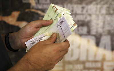 File: A man counts banknotes and traveler checks in Tehran, Iran, August 21, 2019 (AP Photo/Ebrahim Noroozi)