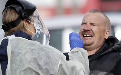A man reacts as a medical staffer tests shoppers who volunteered at a pop-up community COVID-19 testing station at a supermarket carpark in Christchurch, New Zealand, April 17, 2020 (AP Photo/Mark Baker)