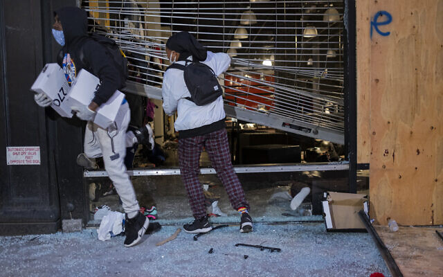 People exit damaged stores after the glass was knocked out in the Chelsea neighborhood of New York, Monday, June 1, 2020. (AP Photo/Craig Ruttle)