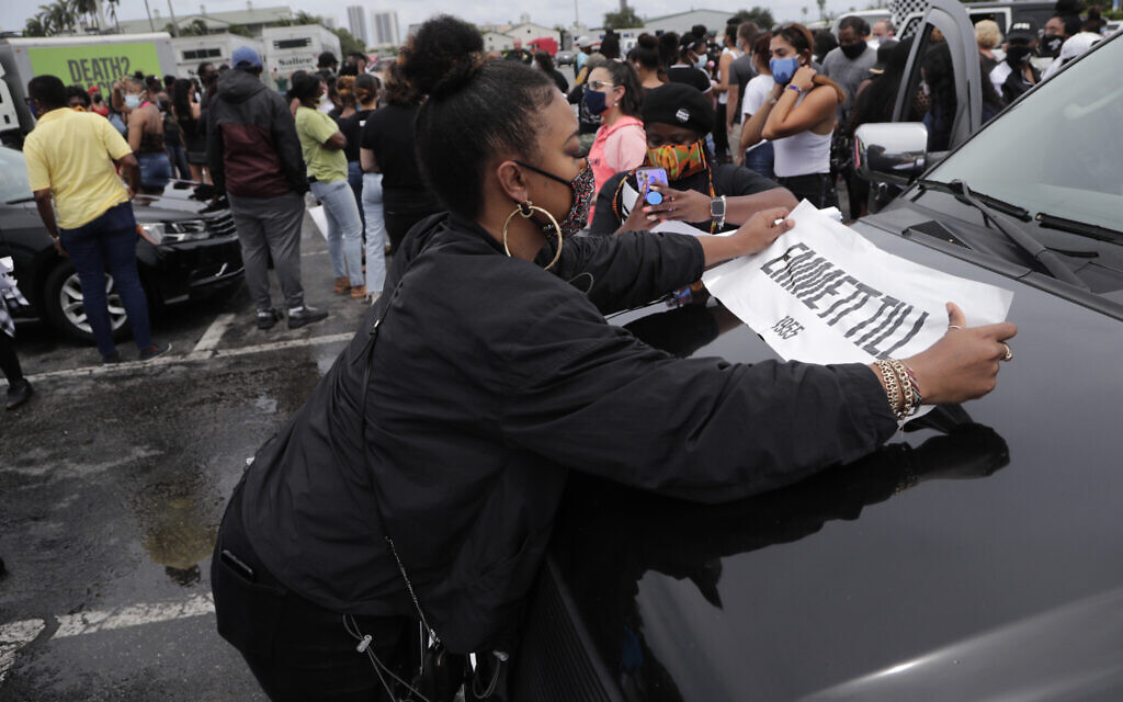 A demonstrator places an Emmett Till sign on a vehicle before a police escorted funeral procession to symbolize a day of mourning for those lives lost due to systemic racism, Wednesday, June 3, 2020, in Hallandale Beach, Florida. (AP Photo/Lynne Sladky)