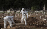 Cemetery workers in protective clothing maneuver the coffin of 57-year-old Paulo Jose da Silva, who died from the new coronavirus, in Rio de Janeiro, Brazil,  June 5, 2020. According to Monique dos Santos, her stepfather mocked the existence of the virus, didn't use a mask, didn't take care of himself, and wanted to shake hands with everybody (AP Photo/Leo Correa)