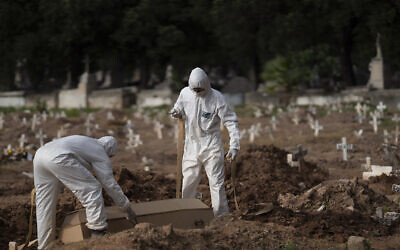 Cemetery workers in protective clothing maneuver the coffin of 57-year-old Paulo Jose da Silva, who died from the new coronavirus, in Rio de Janeiro, Brazil,  June 5, 2020. According to Monique dos Santos, her stepfather mocked the existence of the virus, didn't use a mask, didn't take care of himself, and wanted to shake hands with everybody (AP Photo/Leo Correa)