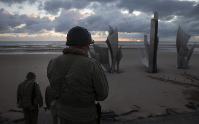 Two men in vintage US WWII uniforms walk toward the Les Braves monument at sunrise prior to a D-Day 76th anniversary ceremony in Saint Laurent sur Mer, Normandy, France, June 6, 2020 (AP Photo/Virginia Mayo) Two men in vintage US WWII uniforms walk toward the Les Braves monument at sunrise prior to a D-Day 76th anniversary ceremony in Saint Laurent sur Mer, Normandy, France, June 6, 2020 (AP Photo/Virginia Mayo)