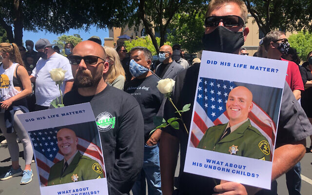 Matthew Rose, left, and Michael Carr, of Santa Cruz County hold posters of slain Sgt. Damon Gutzwiller, as they join others outside the Santa Cruz County Sheriff-Coroner's Office to pay their respects in Santa Cruz, Calif., Sunday, June 7, 2020. (AP Photo/Martha Mendoza) Matthew Rose, left, and Michael Carr, of Santa Cruz County hold posters of slain Sgt. Damon Gutzwiller, as they join others outside the Santa Cruz County Sheriff-Coroner's Office to pay their respects in Santa Cruz, Calif., Sunday, June 7, 2020. (AP Photo/Martha Mendoza)