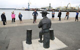People look at the statue of the founder of the Scout movement Robert Baden-Powell on Poole Quay in Dorset, England ahead of its expected removal to "safe storage" following pressure to remove it over concerns about his alleged actions while in the military and "Nazi sympathies" Thursday June 11, 2020. (Andrew Matthews/PA via AP)