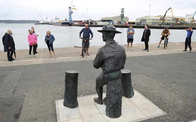 People look at the statue of the founder of the Scout movement Robert Baden-Powell on Poole Quay in Dorset, England ahead of its expected removal to "safe storage" following pressure to remove it over concerns about his alleged actions while in the military and "Nazi sympathies" Thursday June 11, 2020. (Andrew Matthews/PA via AP)