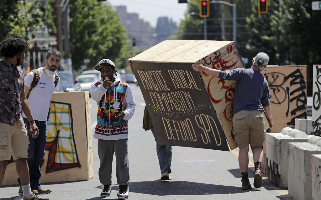 Protesters move a plywood box to further blockade a street adjacent to a closed Seattle police precinct Thursday, June 18, 2020, in Seattle, in what has been named the Capitol Hill Occupied Protest zone. (AP Photo/Elaine Thompson)