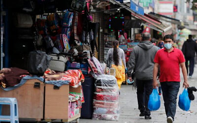 Shoppers walk past opened retail shops as coronavirus restrictions on non-essential retailers were lifted in London, Friday, June 19, 2020. (AP Photo/Frank Augstein)