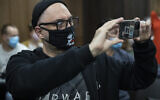 Russian theatre and film director Kirill Serebrennikov wearing a face mask with a portrait of Russian rock singer Viktor Tsoi, takes photos of the media prior to his hearing in a court in Moscow, Russia, June 22, 2020 (AP Photo/Pavel Golovkin)