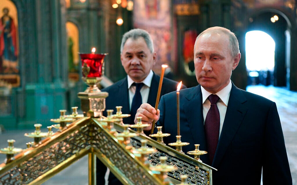 Russian President Vladimir Putin, right, lights a candle with Russian Defense Minister Sergei Shoigu in the background, at the Main Cathedral of the Russian Armed Forces, June 22, 2020. (Alexei Nikolsky, Sputnik, Kremlin Pool Photo via AP)