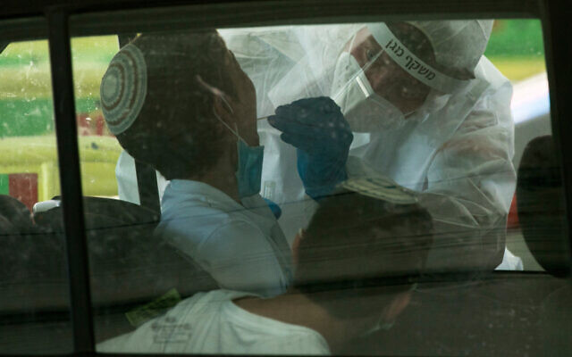 Magen David Adom medical workers test Israelis at a drive-through site to collect samples for coronavirus testing in Jerusalem on May 31, 2020. (Olivier Fitoussi/Flash90) Magen David Adom medical workers test Israelis at a drive-through site to collect samples for coronavirus testing in Jerusalem on May 31, 2020. (Olivier Fitoussi/Flash90)