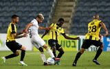 Illustrative: A Maccabi Tel Aviv player, in white, dribbles the ball between opposing players during a match against Beitar Jerusalem in Jerusalem on June 8, 2020. (Flash90)