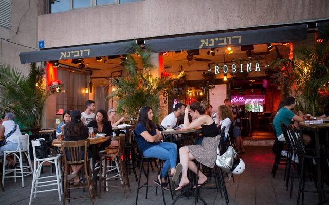 Israelis, some wearing protective face masks and some not, sit at an eatery in Tel Aviv on June 9, 2020. (by Miriam Alster/Flash90) Israelis, some wearing protective face masks and some not, sit at an eatery in Tel Aviv on June 9, 2020. (by Miriam Alster/Flash90)