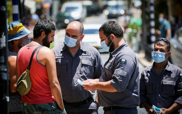 Inspectors talk to people who are not wearing face mask in the northern Israeli city of Tzfat, June 15, 2020. (David Cohen/Flash90) Inspectors talk to people who are not wearing face mask in the northern Israeli city of Tzfat, June 15, 2020. (David Cohen/Flash90)