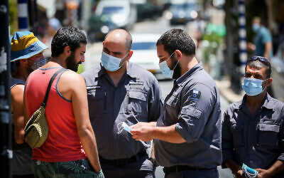 Inspectors talk to a man not wearing a face mask in the northern city of Safed on June 15, 2020. (David Cohen/ Flash90)