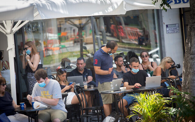 Israelis, some wearing protective face masks and some not, at a cafe in Tel Aviv on June 16, 2020. (Miriam Alster/Flash90) Israelis, some wearing protective face masks and some not, at a cafe in Tel Aviv on June 16, 2020. (Miriam Alster/Flash90)