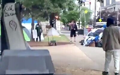 Screen capture from video showing the moment a man, center middle-distance and with his back to the camera, opens fire at a protest rally in a park,  Louisville, Kentucky, June 27, 2020. (Twitter)