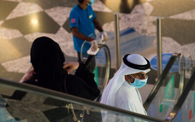 An Emirati man and woman ride an escalator at Mall of the Emirates in Dubai, United Arab Emirates, as the country loosens its coronavirus restrictions, May 27, 2020. (AP Photo/Jon Gambrell)