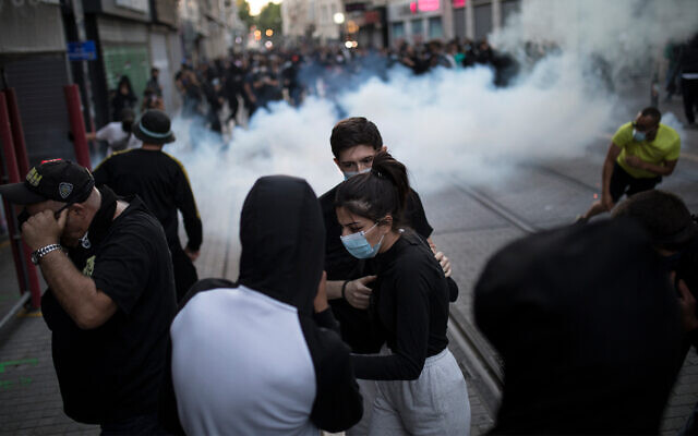 Protesters react to tear gas fired by French riot police during a march against police brutality and racism in Marseille, France, June 13, 2020. (AP/Daniel Cole) Protesters react to tear gas fired by French riot police during a march against police brutality and racism in Marseille, France, June 13, 2020. (AP/Daniel Cole)