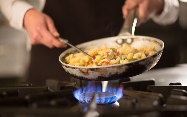 Illustrative: A cook prepares a dish on a stove. (iStock by Getty Images)