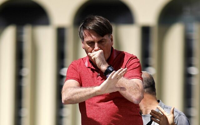 Brazilian President Jair Bolsonaro coughs as he speaks after joining supporters who were taking part in a motorcade to protest against quarantine and social distancing measures against the coronavirus outbreak, on April 19, 2020, in Brasilia. (Sergio Lima/AFP) Brazilian President Jair Bolsonaro coughs as he speaks after joining supporters who were taking part in a motorcade to protest against quarantine and social distancing measures against the coronavirus outbreak, on April 19, 2020, in Brasilia. (Sergio Lima/AFP)