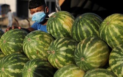 A mask-clad child sells watermelons in the Askar refugee camp, east of the West Bank city of Nablus, amid the novel coronavirus pandemic crisis, on July 13, 2020. ( JAAFAR ASHTIYEH / AFP)