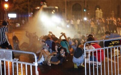 Israel police use water cannons as they clash with people during a protest against Israeli Prime Minister Benjamin Netanyahu outside his official residence in Jerusalem, on July 14, 2020. (MENAHEM KAHANA / AFP)