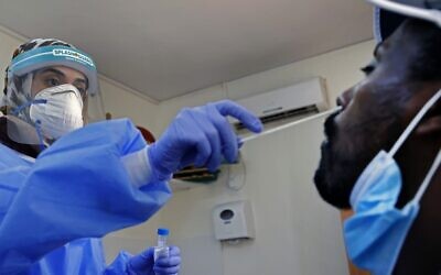 A medic collects a swab sample from a man at a coronavirus testing facility in Or Yehuda, on July 22, 2020. (Jack Guez/ AFP)