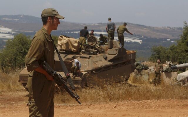 An Israeli soldier stands near a Namer Infantry Fighting Vehicle near the town of Avivim in northern Israel along the border with Lebanon, on July 23, 2020. (JALAA MAREY / AFP)
