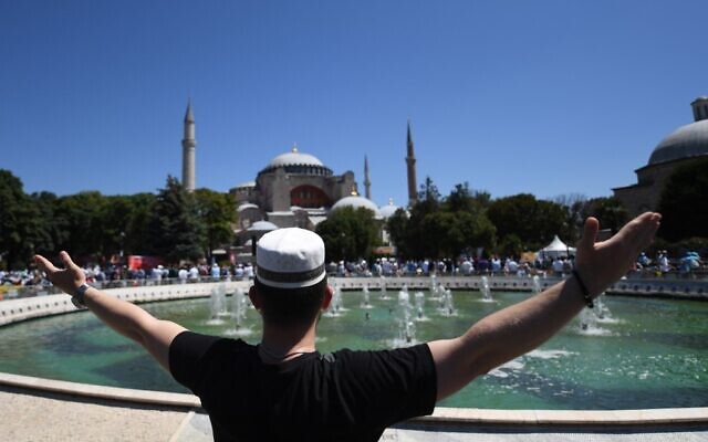A man raises his arms as people gathe on July 24, 2020 outside Hagia Sophia in Istanbul to attend the Friday prayer, the first Muslim prayer held at the landmark since it was reconverted to a mosque despite international condemnation. (OZAN KOSE / AFP)
