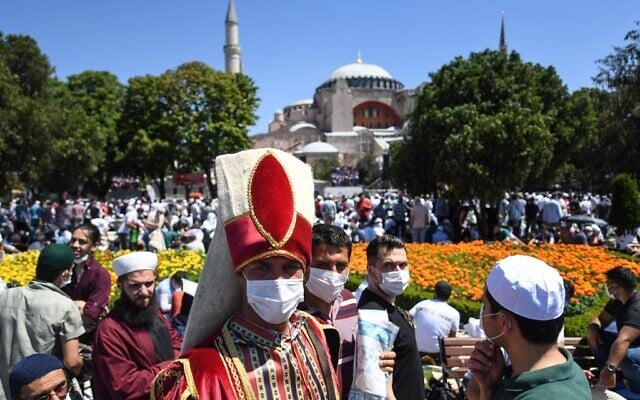 A man wearing a traditional Ottoman costume arrives with others on July 24, 2020 outside Hagia Sophia in Istanbul to attend the Friday prayer, the first Muslim prayer held at the landmark since it was reconverted to a mosque despite international condemnation. (OZAN KOSE / AFP)