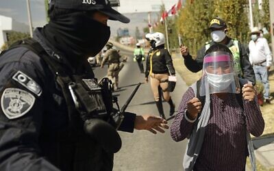 A policeman stops Celia Capira Mamani, while attempting to reach the car of Peru's President Martin Vizcarra to demand medical attention for her husband Adolfo Mamani Tacuri, infected with the novel coronavirus COVID-19, during the latter's visit to the Honorio Delgado Hospital in the southern Andean city of Arequipa on July 19, 2020 (Denis MAYHUA / AFP)