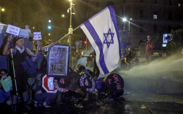 Protesters crouch down as police use water cannons against them in Jerusalem on July 25, 2020. (AHMAD GHARABLI / AFP) Protesters crouch down as police use water cannons against them in Jerusalem on July 25, 2020. (AHMAD GHARABLI / AFP)