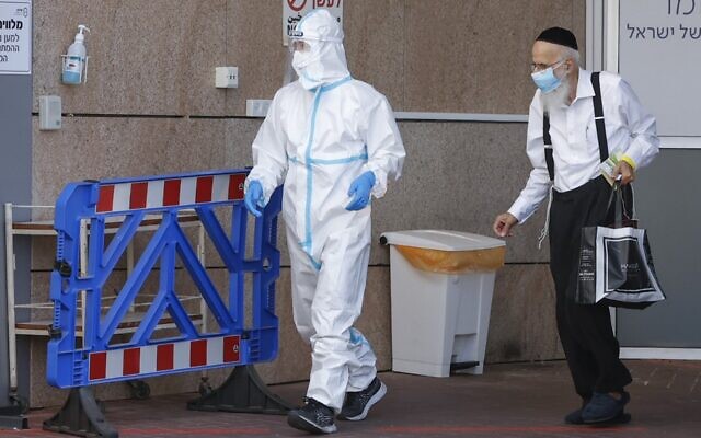A medical worker in a protective suit accompanies a man who tested positive for COVID-19 at Sheba Medical Center in Ramat Gan on July 26, 2020. (Jack Guez/AFP) A medical worker in a protective suit accompanies a man who tested positive for COVID-19 at Sheba Medical Center in Ramat Gan on July 26, 2020. (Jack Guez/AFP)