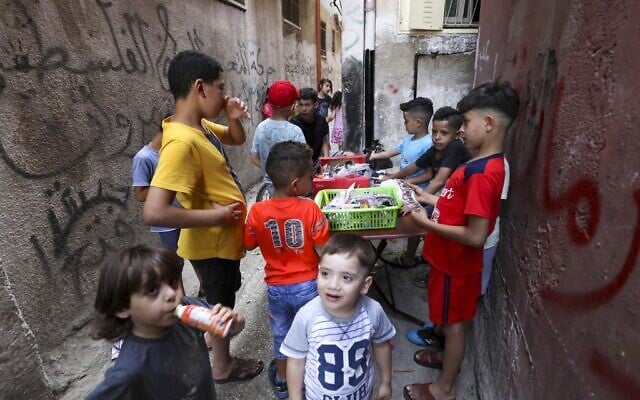 Palestinian children gather around a street vendor in the Amari refugee camp near the West Bank city of Ramallah on July 29, 2020. (ABBAS MOMANI / AFP) Palestinian children gather around a street vendor in the Amari refugee camp near the West Bank city of Ramallah on July 29, 2020. (ABBAS MOMANI / AFP)