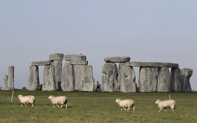 Sheep graze as security guards patrol the prehistoric monument at Stonehenge in southern England, on April 26, 2020, closed during the national lockdown due to the novel coronavirus COVID-19 pandemic.  (Adrian DENNIS / AFP)