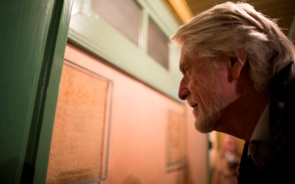 A visitor examines pencil marks measuring the growth of Anne and Margot Frank in what used to be their parents' room, at the Anne Frank House museum in Amsterdam, November 24, 2016. (Photo Collection Anne Frank House/ via JTA)