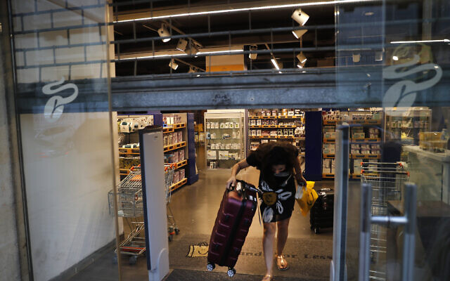 A customer carries luggage out of an international fashion and home-ware retailer temporarily shutting down, in Beirut, Lebanon, on July 2, 2020. (AP Photo/Hussein Malla) A customer carries luggage out of an international fashion and home-ware retailer temporarily shutting down, in Beirut, Lebanon, on July 2, 2020. (AP Photo/Hussein Malla)
