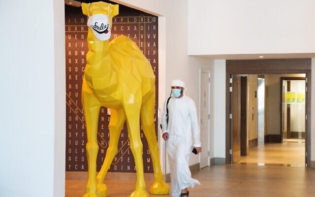 An Emirati wearing a face mask due to the coronavirus pandemic walks past a camel statue decorated with a face mask at the Rove City Centre Hotel in Dubai, United Arab Emirates, July 6, 2020. (Jon Gambrell/AP) An Emirati wearing a face mask due to the coronavirus pandemic walks past a camel statue decorated with a face mask at the Rove City Centre Hotel in Dubai, United Arab Emirates, July 6, 2020. (Jon Gambrell/AP)