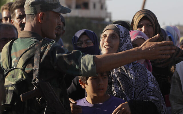 In this August 15, 2018 file photo, a woman talks with a soldier of the Syrian army during distribution of humanitarian aid from the Russian military in the town of Rastan, Syria. (AP Photo/Sergei Grits, File) In this August 15, 2018 file photo, a woman talks with a soldier of the Syrian army during distribution of humanitarian aid from the Russian military in the town of Rastan, Syria. (AP Photo/Sergei Grits, File)