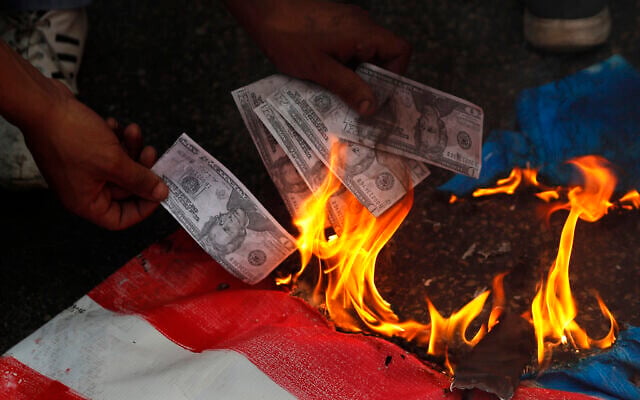 A supporter of a communist group burns representation of US currency, during a protest against US interference in Lebanon's affairs, near the US embassy, in Aukar northeast of Beirut, Lebanon, July 10, 2020. (Hussein Malla/AP) A supporter of a communist group burns representation of US currency, during a protest against US interference in Lebanon's affairs, near the US embassy, in Aukar northeast of Beirut, Lebanon, July 10, 2020. (Hussein Malla/AP)