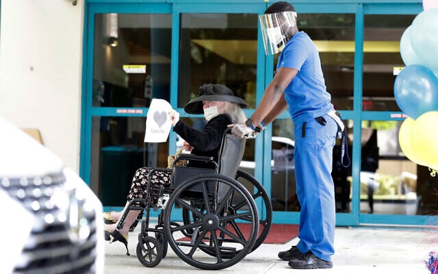Margaret Choinacki, center, 87, who has no other family members left because her husband and daughter have died, waves goodbye after a drive-by visit by her friend Frances Reaves, as resident care coordinator Anggy Volmar, right, wheels her back inside, Friday, July 17, 2020, at Miami Jewish Health in Miami (AP Photo/Wilfredo Lee) Margaret Choinacki, center, 87, who has no other family members left because her husband and daughter have died, waves goodbye after a drive-by visit by her friend Frances Reaves, as resident care coordinator Anggy Volmar, right, wheels her back inside, Friday, July 17, 2020, at Miami Jewish Health in Miami (AP Photo/Wilfredo Lee)