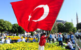 A man waves a Turkish flag outside the Byzantine-era Hagia Sophia, in the historic Sultanahmet district of Istanbul, Friday, July 24, 2020.  (AP Photo/Omer Kuscu)
