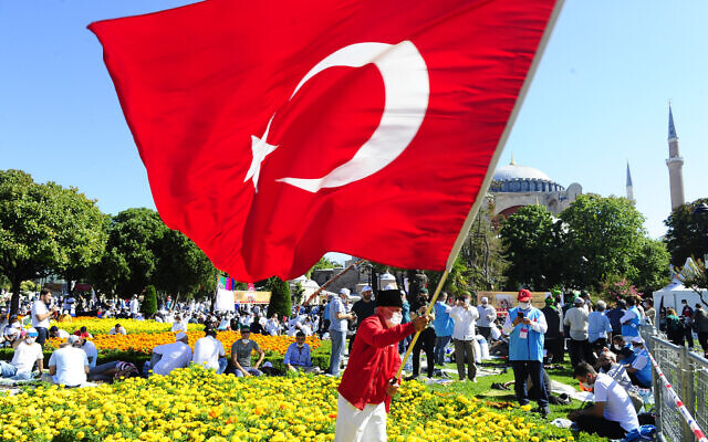 A man waves a Turkish flag outside the Byzantine-era Hagia Sophia, in the historic Sultanahmet district of Istanbul, Friday, July 24, 2020.  (AP Photo/Omer Kuscu)