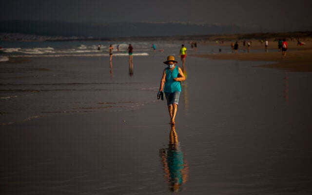 A woman wearing a face mask walks at the beach in Zahara de los Atunes, Cadiz province, south of Spain, on July 25, 2020. (AP Photo/Emilio Morenatti) A woman wearing a face mask walks at the beach in Zahara de los Atunes, Cadiz province, south of Spain, on July 25, 2020. (AP Photo/Emilio Morenatti)