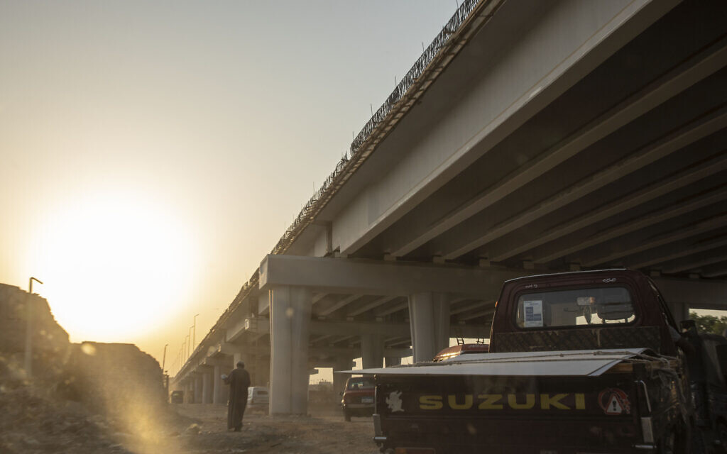 A man walks under a new highway flyover under construction through the Southern Cemetery, part of the City of the Dead, a UNESCO World Heritage Site, in Cairo, Egypt, July 28, 2020. (AP Photo/Nariman El-Mofty)
